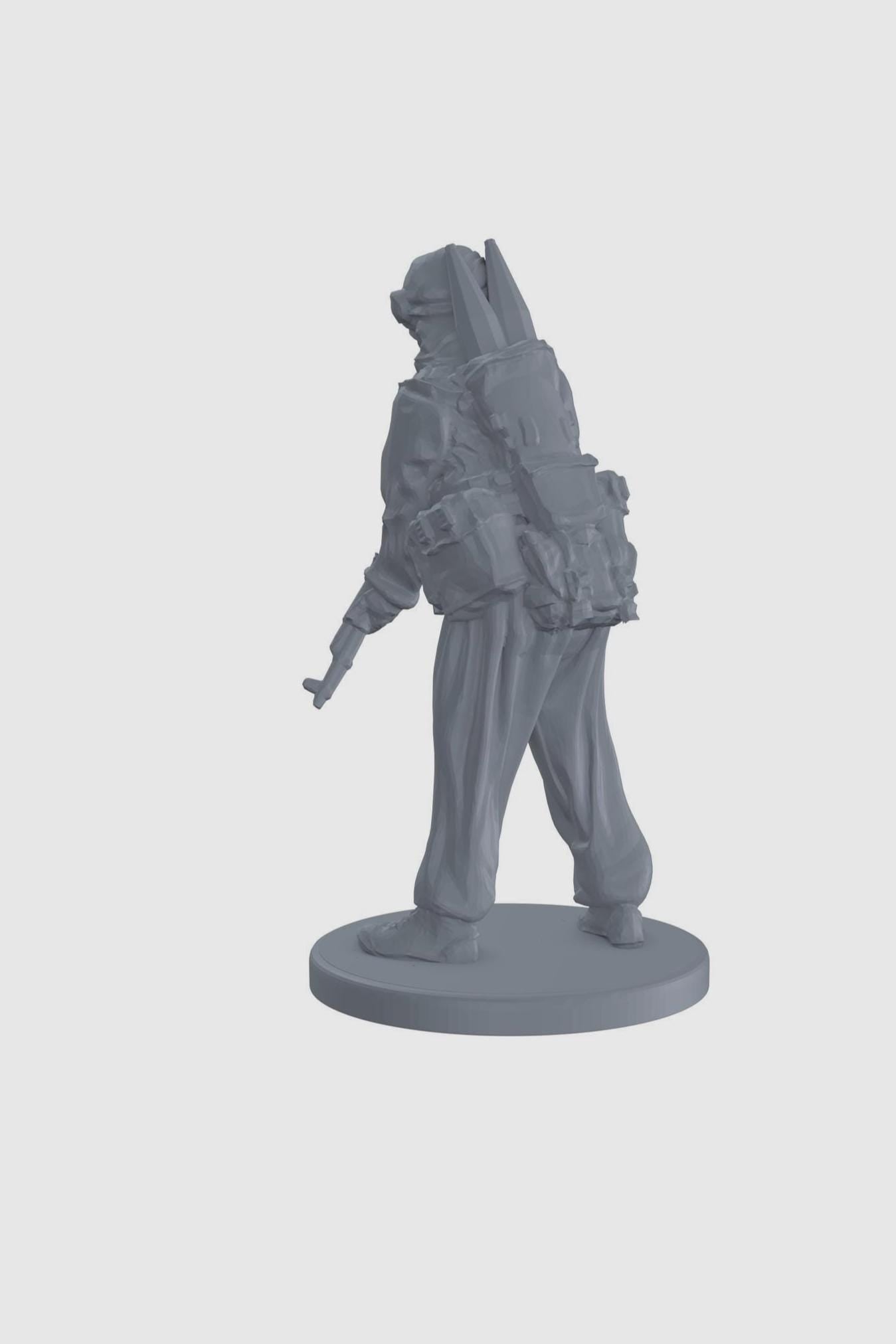 May include: A gray plastic miniature figurine of a soldier wearing a headscarf and holding a rifle. The soldier is standing on a round base.