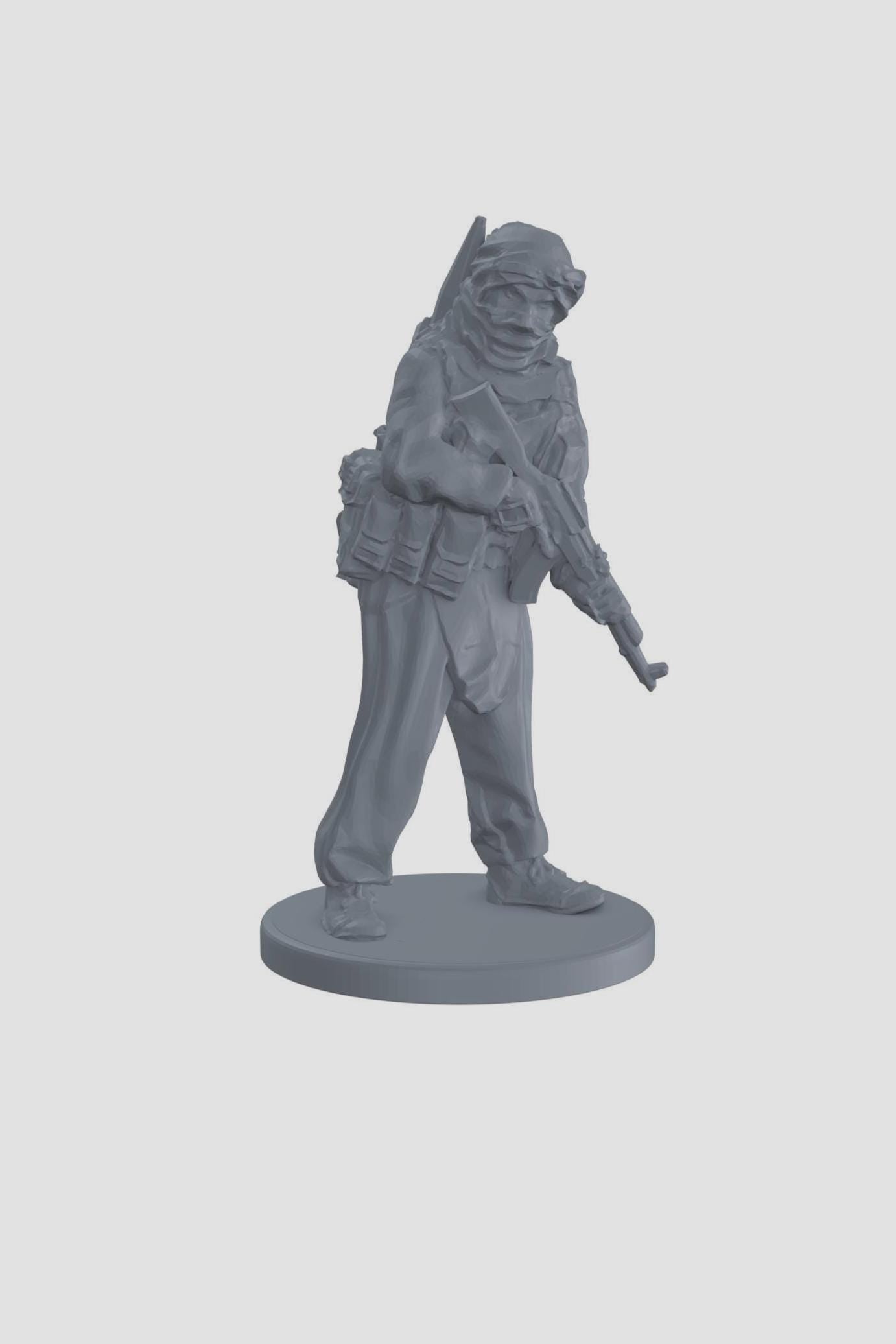 May include: A gray plastic miniature figurine of a soldier wearing a headscarf and holding a rifle. The soldier is standing on a round base.